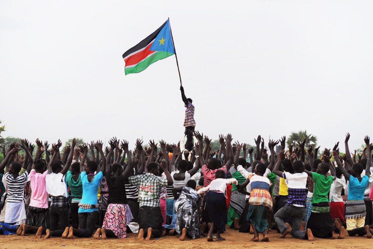 A young man raises the South Sudanese flag above a cheering crowd at Peace Cultural Day