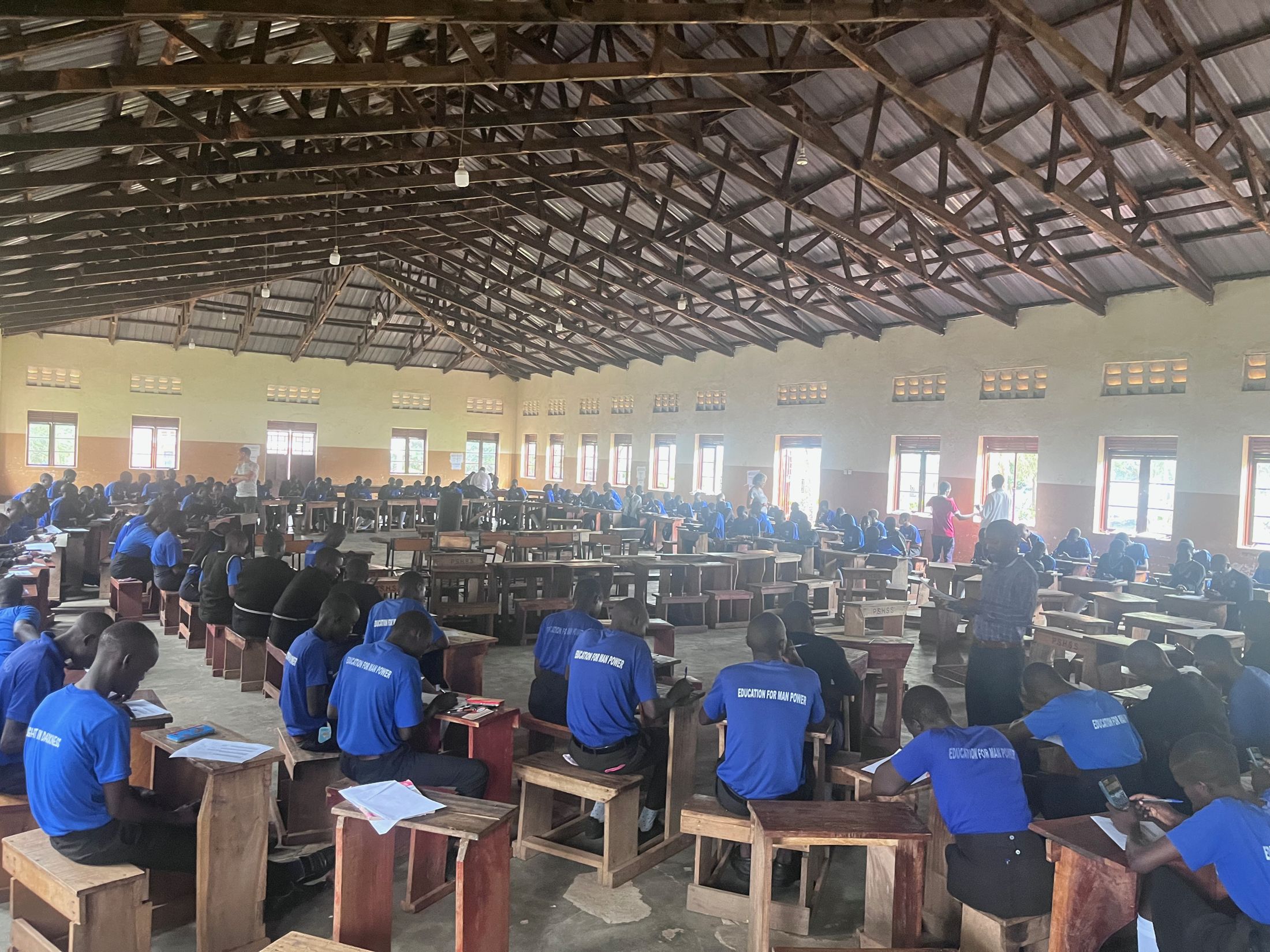 A hall full of students writing at wooden desks